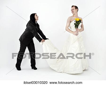 Bride Wearing A Suit While Holding The Train Of A Wedding Dress