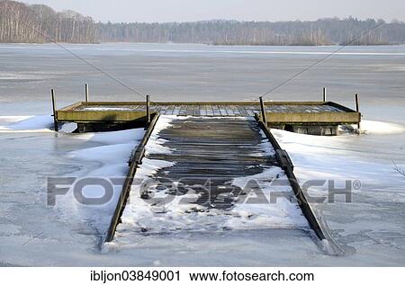 Stock Image - "Bridge in ice on Snogeholmssjon lake, Skane, Sweden, Europe". Fotosearch