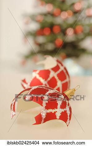 Picture - Broken christmas bauble lying in front of a Christmas tree. Fotosearch