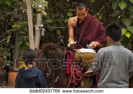 Stock Photo - "Buddhist monk on horseback with a begging bowl collecting alms in the morning, temple and monastery of Wat Phra Archa Thong or Golden Horse Temple, Mae Chan, Chiang Rai Province, Northern Thailand, Thailand, Asia". Fotosearch