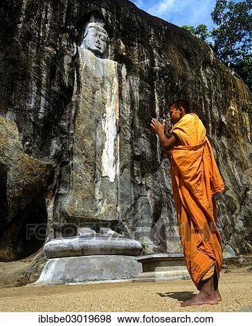 Stock Photo - "Buddhist monk praying in front of the Deepangkara Buddha statue, Buduruvagala, rock of Buddhist sculptures, Buduruvagala, Budurula, Wellawaya, Monaragala Distrikt, Sri Lanka, Asia". Fotosearch