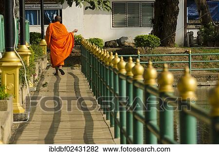 Stock Image - "Buddhist monk walking across a bridge, Mae Hong Son, Northern Thailand, Thailand, Asia". Fotosearch