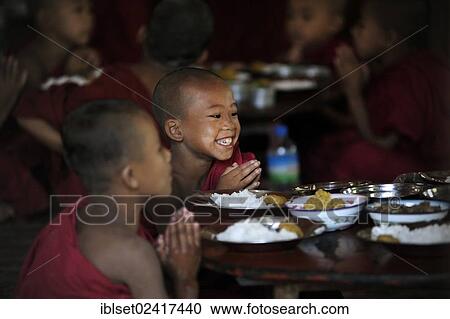 Stock Image - Buddhist novices praying before eating their meal in a monastery, Myanmar, Burma, Southeast Asia, Asia. Fotosearch