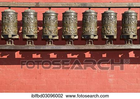 Stock Image - "Buddhist prayer wheels in front of a red wall at Swayambhunath Stupa, Monkey Temple, Kathmandu Valley, Kathmandu, Kathmandu District, Bagmati Zone, Nepal, Asia". Fotosearch