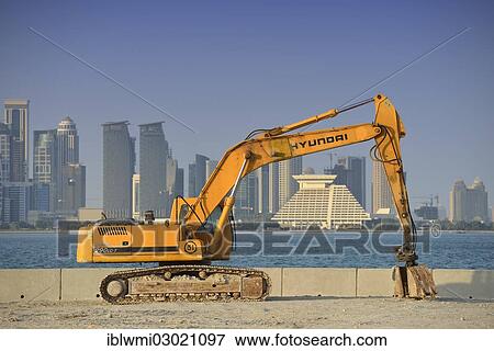 Stock Photo - "Building boom in Doha, Hyundai excavator in front of the skyline of Doha with Doha Sheraton Hotel, Four Seasons Hotel, Falcon and Pearl Towers, Doha Corniche, Doha, Doha, Qatar, Asia". Fotosearch