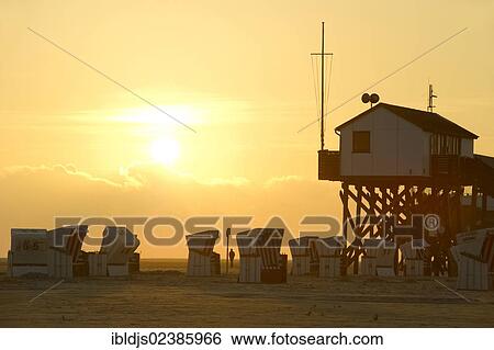 Stock Photograph - "Building on stilts and roofed wicker beach chairs on the beach of St. Peter-Ording, North Frisia, Schleswig-Holstein, Germany, Europe". Fotosearch