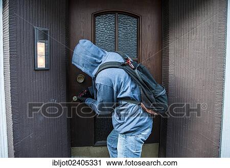 Stock Image - Burglar prying open a door in broad daylight. Fotosearch