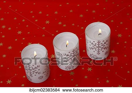Burning candles standing on red Christmas wrapping paper View Large Photo Image Picture - Burning candles standing on red Christmas wrapping paper. Fotosearch