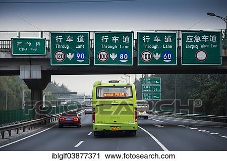 Stock Image - "Bus travelling on 3-lane motorway with signs and a bridge, Beijing, China, Asia". Fotosearch