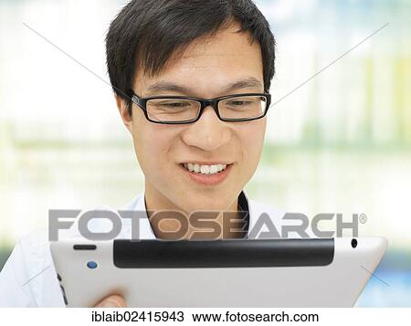 Businessman, Asian, with glasses, iPad, smiling, friendly, successful, optimistic, positive, in the office View Large Photo Image Stock Image - Businessman, Asian, with glasses, iPad, smiling, friendly, successful, optimistic, positive, in the office. Fotosearch