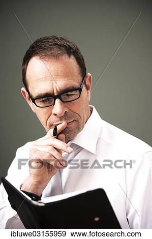 "Businessman wearing glasses looking at his appointment calendar, Mannheim, Baden-Wurttemberg, Germany, Europe" View Large Photo Image Stock Photo - "Businessman wearing glasses looking at his appointment calendar, Mannheim, Baden-Wurttemberg, Germany, Europe". Fotosearch