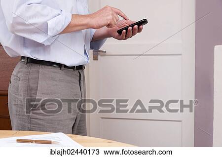 Businessman working at home using a smartphone View Large Photo Image Stock Image - Businessman working at home using a smartphone. Fotosearch