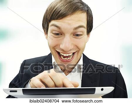 Picture - "Businessman working on an iPad, focused, happy, portrait". Fotosearch