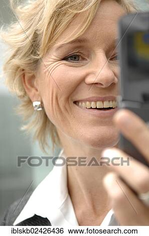 Stock Photograph - "Businesswoman, 40-50, looking at a cell phone". Fotosearch