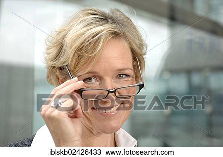 Stock Image - "Businesswoman, 40-50, looking over the edge of her glasses, portrait". Fotosearch