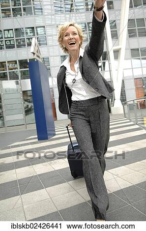 "Businesswoman, 40-50, wavimg while pulling a rolling suitcase" View Large Photo Image Stock Image - "Businesswoman, 40-50, wavimg while pulling a rolling suitcase". Fotosearch