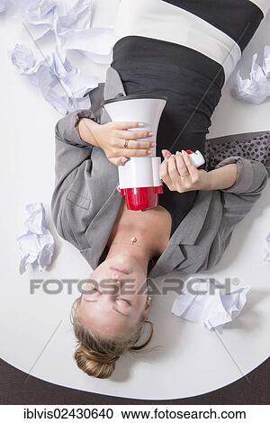 "Businesswoman having a break, lying on her desk, exhausted from stress in her workplace, holding a megaphone in her hands" View Large Photo Image Stock Image - "Businesswoman having a break, lying on her desk, exhausted from stress in her workplace, holding a megaphone in her hands". Fotosearch