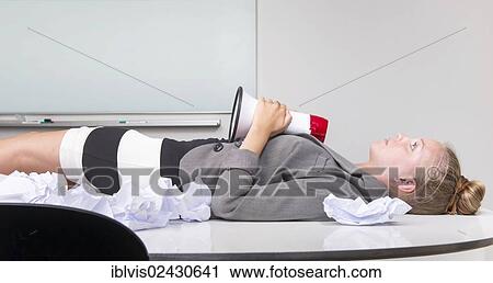 "Businesswoman having a break, lying on her desk, exhausted from stress in her workplace, holding a megaphone in her hands" View Large Photo Image Stock Image - "Businesswoman having a break, lying on her desk, exhausted from stress in her workplace, holding a megaphone in her hands". Fotosearch