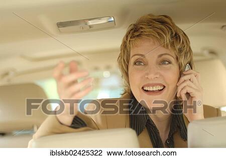 Stock Image - Businesswoman making a phone call in a car. Fotosearch