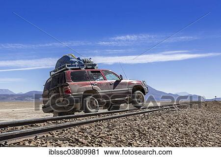 Stock Image - "Car crossing railroad tracks, Altiplano, Andean Plateau, Andes, Bolivia, South America". Fotosearch