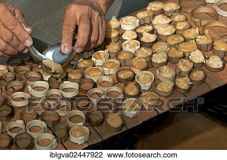 Stock Image - "Caramelized palm sugar being filled into small moulds made of strips of palm leaves for the production of traditional palm sugar candies, Siem Reap, Cambodia, Southeast Asia, Asia". Fotosearch
