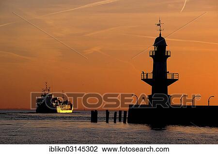 "Cargo ship and silhouette of the Brunsbuettel Mole 1 lighthouse in front of a evening sky, Brunsbuttel, Schleswig-Holstein, Germany, Europe" View Large Photo Image Stock Image - "Cargo ship and silhouette of the Brunsbuettel Mole 1 lighthouse in front of a evening sky, Brunsbuttel, Schleswig-Holstein, Germany, Europe". Fotosearch