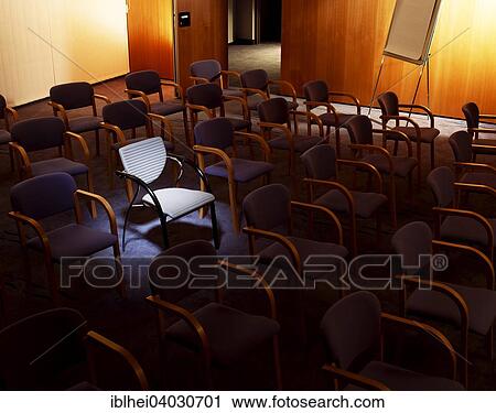 Stock Image - "Chairs in a lecture hall, a chair is illuminated". Fotosearch