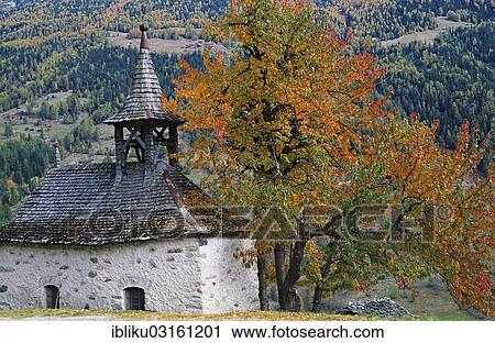 Stock Image - "Chapel of Grimentz with trees in autumn, Val d'Anniviers, Grimentz, Lower Valais, Canton of Valais, Switzerland, Europe". Fotosearch