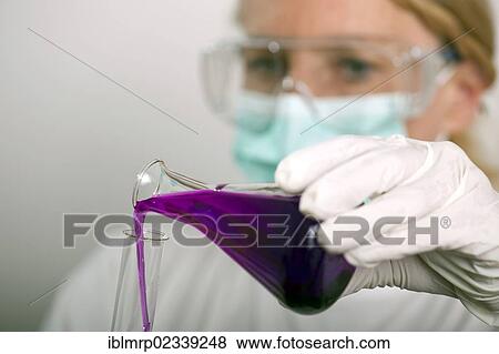 Stock Photo - Chemist pouring a liquid from a flask into a test tube. Fotosearch