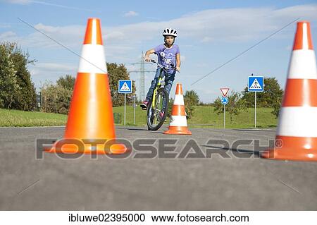 Stock Image - Child practicing to ride slalom on a bicycle at a traffic awareness course. Fotosearch