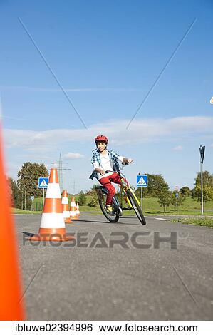 Stock Photograph - Child practicing to ride slalom on a bicycle at a traffic awareness course. Fotosearch