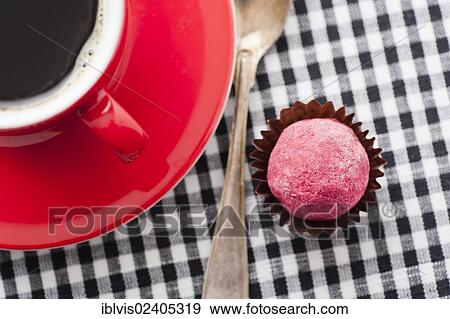 Stock Photo - Chocolate truffle beside to a red coffee cup. Fotosearch