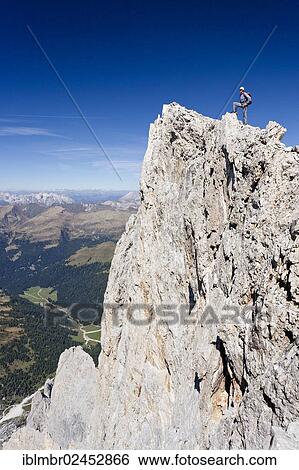 Stock Photograph - "Climber on the summit of Cima Vezzena Mountain in the Pala Group, overlooking the Dolomites with the Rosengarten Group, Trentino, Italy, Europe". Fotosearch