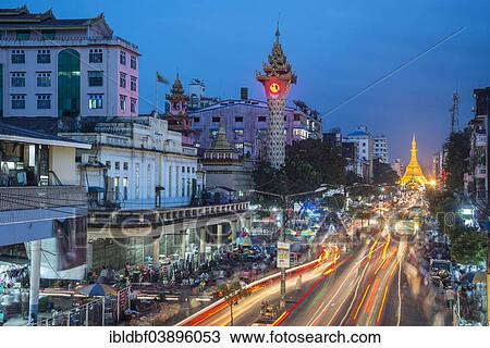 Stock Image - "Clock tower, Sule Pagoda at the back, at dusk, blue hour, road traffic, Yangon or Rangoon, Yangon Region, Myanmar, Asia". Fotosearch