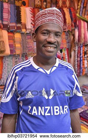 "Clothing merchant wearing a football jersey of the Zanzibar Heroes, Stone Town, Zanzibar City, Zanzibar, Tanzania, Africa" View Large Photo Image Picture - "Clothing merchant wearing a football jersey of the Zanzibar Heroes, Stone Town, Zanzibar City, Zanzibar, Tanzania, Africa". Fotosearch