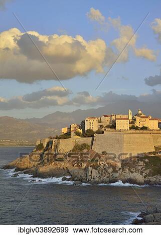 Stock Photo - "Cloudy atmosphere over the citadel in the evening light, Calvi, Corsica, France, Europe". Fotosearch