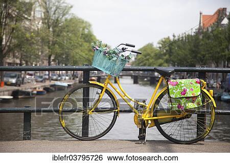 Stock Photograph - "Colourful bicycle parked on a bridge, Amsterdam, Netherlands". Fotosearch
