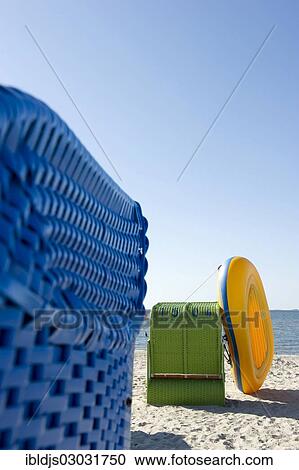 Stock Image - "Colourful roofed wicker beach chairs and a yellow inflatable boat, Amrum, North Frisian Islands, Schleswig-Holstein, Germany, Europe". Fotosearch