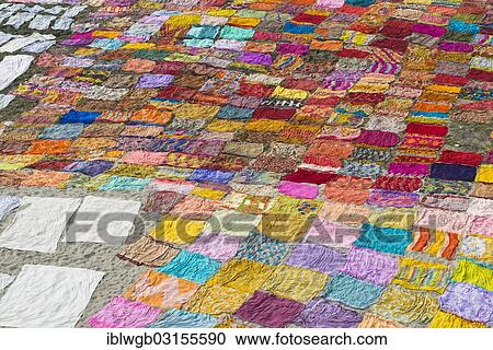 Stock Image - "Colourful saris are laid out on the sand for drying after washing, Agra, Uttar Pradesh, India, Asia". Fotosearch