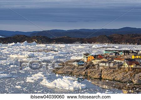 Stock Image - "Colourful timber houses by the sea with iceberg fragments, Ilulissat, Greenland, North America". Fotosearch