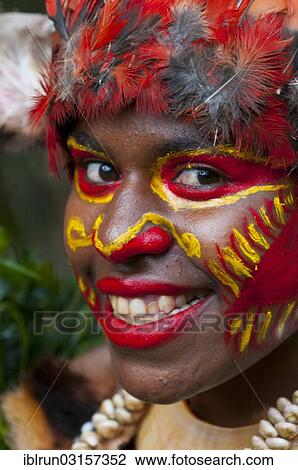 Stock Image - "Colourfully decorated woman with face paint is celebrating at the traditional Sing Sing gathering in the highlands, Paya, Papua New Guinea, Oceania". Fotosearch