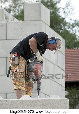 "Construction worker drilling holes into concrete blocks during a building site load test at a construction site in Fridolfing, Bavaria, Germany, Europe" View Large Photo Image Stock Image - "Construction worker drilling holes into concrete blocks during a building site load test at a construction site in Fridolfing, Bavaria, Germany, Europe". Fotosearch