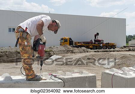 "Construction worker drilling holes into stone blocks that are to be used at a building site load test at a construction site in Fridolfing, Bavaria, Germany, Europe" View Large Photo Image Stock Image - "Construction worker drilling holes into stone blocks that are to be used at a building site load test at a construction site in Fridolfing, Bavaria, Germany, Europe". Fotosearch