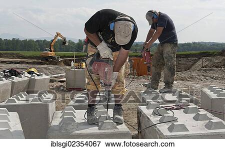 "Construction workers drilling holes into concrete blocks during a building site load test at a construction site in Fridolfing, Bavaria, Germany, Europe" View Large Photo Image Stock Photo - "Construction workers drilling holes into concrete blocks during a building site load test at a construction site in Fridolfing, Bavaria, Germany, Europe". Fotosearch