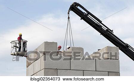 Stock Image - "Construction workers stacking concrete blocks during a building site load test, construction site in Fridolfing, Bavaria, Germany, Europe". Fotosearch