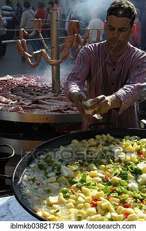 "Cook adds pieces of onion to a large pan containing potato stew in front of giant barbecue at the annual All Saints Market in Cocentaina, Alicante province, Spain, Europe" View Large Photo Image Stock Photo - "Cook adds pieces of onion to a large pan containing potato stew in front of giant barbecue at the annual All Saints Market in Cocentaina, Alicante province, Spain, Europe". Fotosearch