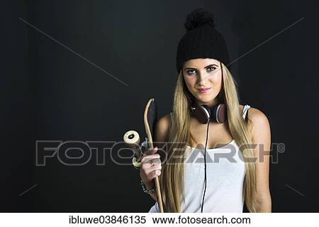 Stock Photography - Cool young woman with a skateboard and headphones. Fotosearch