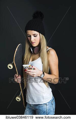 Stock Photo - "Cool young woman with a skateboard, headphones and a mobile phone". Fotosearch