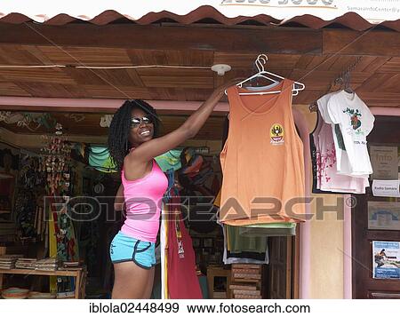 Stock Photo - "Costa Rican woman, 35, hanging up t-shirts in a boutique, Playa Samara, Nicoya Peninsula, Costa Rica, Central America, North America". Fotosearch