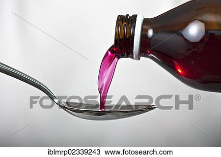Stock Image - Cough syrup is poured from a brown glass bottle onto a spoon. Fotosearch